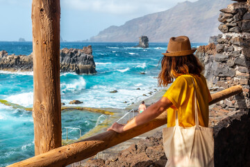 A tourist looking at the pools from the recreational area of La Maceta on the island of El Hierro,...