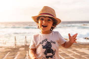 Portrait of boy in hat enjoying summer sunset on the beach, children's vacation