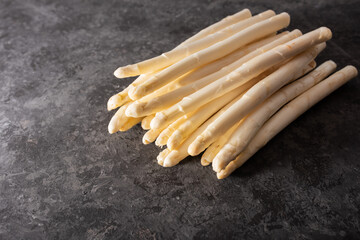 Fresh white asparagus on black background. Seasonal spring vegetables on black stone slab. Sunny...
