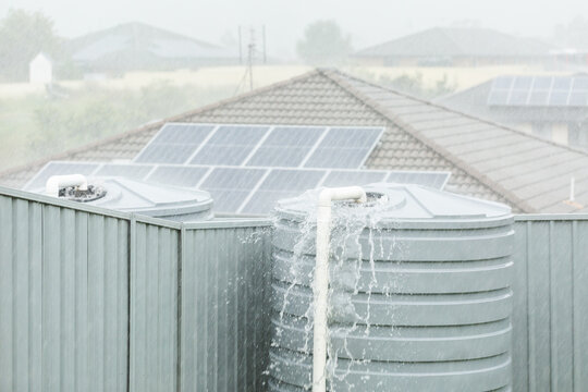 Heavy rainfall in backyard with water overflowing from tank