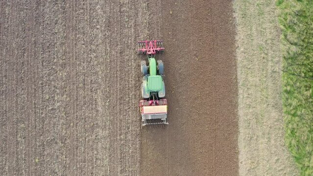 Tractor with seed drill and Front Packer compacts the soil. Hessen Germany. Drone footage Straight Down of a farmer tractor working the land.