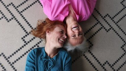 senior lesbian women, two mature women lying on carpet together, looking at camera, happy senior women couple
