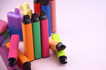 Set of multicolor disposable electronic cigarettes on a pink background.