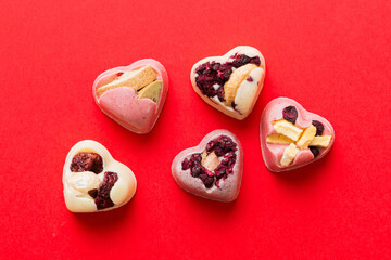 chocolate sweets in the form of a heart with fruits and nuts on a colored background. top view with space for text, holiday concept