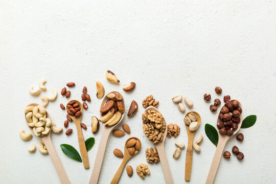 mixed nuts in white wooden spoon. Mix of various nuts on colored background. pistachios, cashews, walnuts, hazelnuts, peanuts and brazil nuts