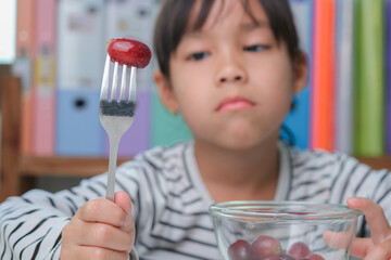 Children don't like to eat fruits. Cute young Asian girl refusing to eat healthy fruits. Nutrition...
