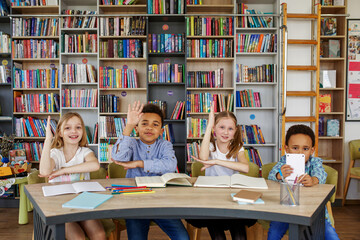 Multi-ethnic pupils study and write at table in library or classroom. Back to school.