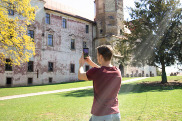 young man takes pictures on a mobile phone in the old town. Photo. Journey. Back view