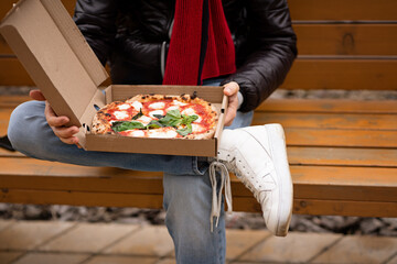 Food delivery. Ordering dinner online from a restaurant. Neapolitan pizza and a walk around the city. Let's bring food to the air. Margherita - pizza with mozzarella and basil. Cardboard box.