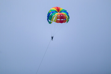 the man flying in the clear sky with parachute doing para gliding