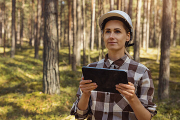 female forester or forest engineer working in the woods with digital tablet. forestry, forest...