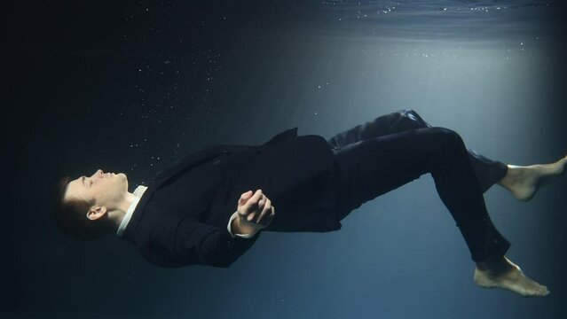Businessman man in a suit, drowning under water.