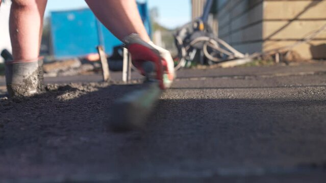 Concrete worker leveling fresh wet surface with wooden float