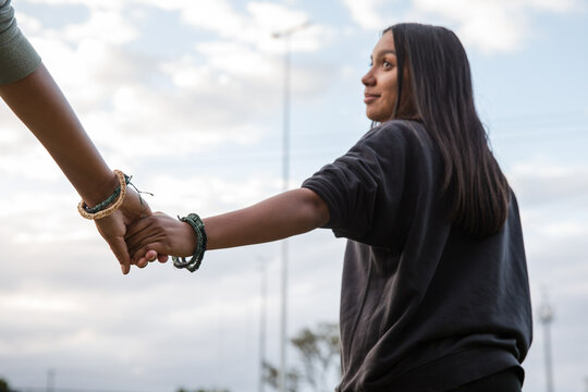 Two Aboriginal girls, outdoors holding hands, wearing traditional woven bracelets