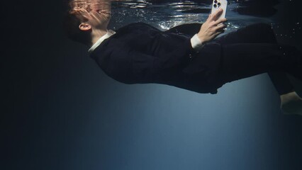 Businessman, a man in a suit, talking on a mobile phone and drowning.