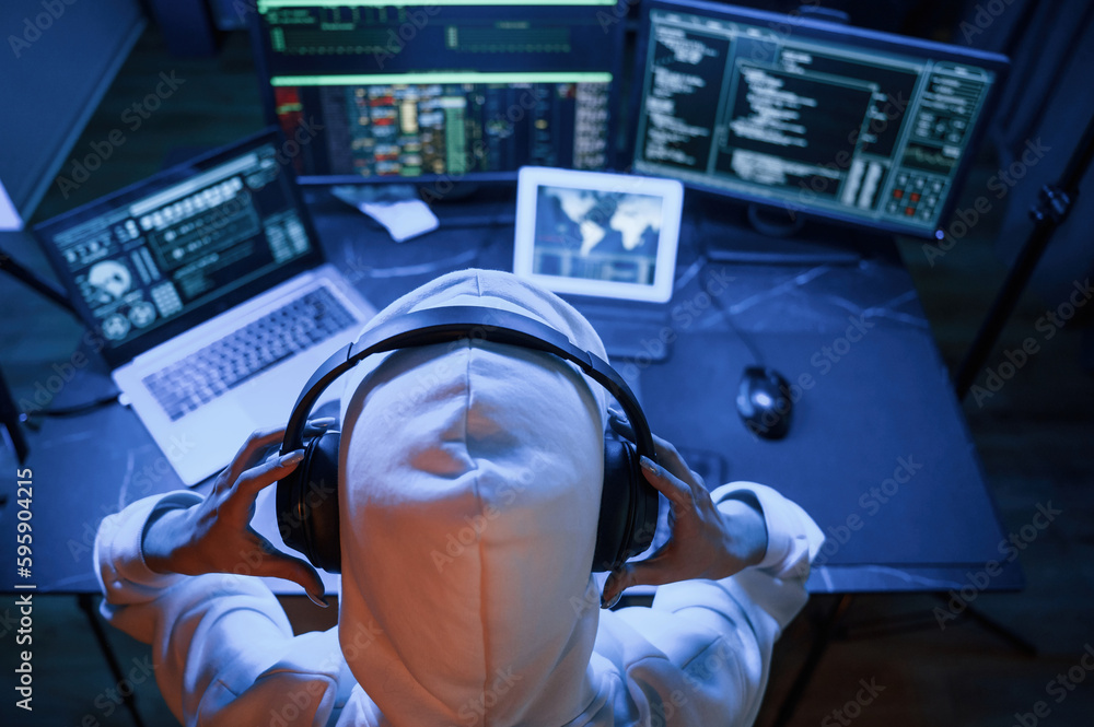 Poster top view. young professional female hacker is indoors by computer with lot of information on display