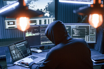 Rear view. Male professional hacker is sitting by computer, conception of virus