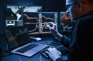 Financial Analyst Working on a Computer with Multi-Monitor Workstation with Real-Time Stocks, Commodities and Exchange Market Charts.