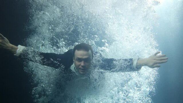 A businessman in a suit swims through the swirling current.