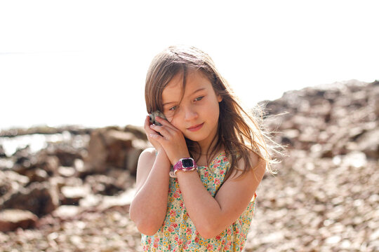 Young girl listening to a seashell on the beach