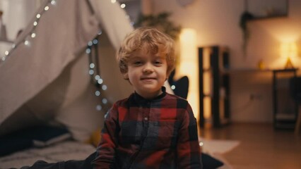 Portrait of cute little boy sitting in front of blanket fort at home, innocence