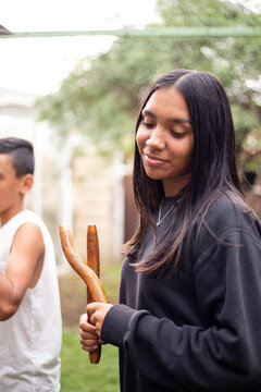 Aboriginal teenage girl with musical sticks in her backyard  with her brother