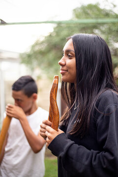 Aboriginal teenage girl with musical sticks in her backyard  with her brother