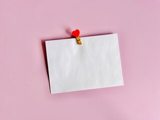 Overhead view of a blank white envelope with a heart clothes peg