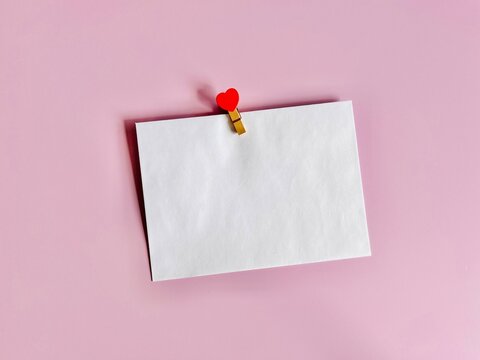 Overhead view of a blank white envelope with a heart clothes peg