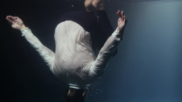 A businessman man in a suit, floundering in the water and drowning.