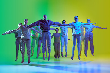 Group of teenagers, young dancers jumping together over green and yellow gradient background in...
