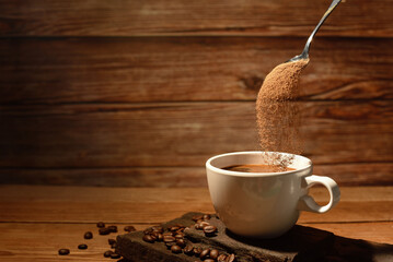 pouring coffee powder on coffee cup on brown wooden borrd background