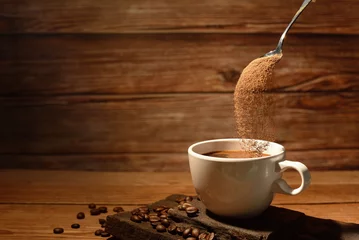 Crédence de cuisine en verre imprimé Café pouring coffee powder on coffee cup on brown wooden borrd background