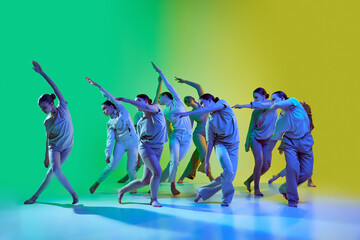 Group of young beautiful girls, dancers moving to the beat of the music on gradient background in...