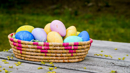 Colored Easter eggs in small basket outside on table with copy spaceff