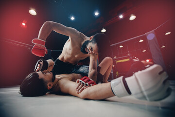 MMA hit knockdown. Boxers fighter finishes off enemy in ring octagon, dark background spot light