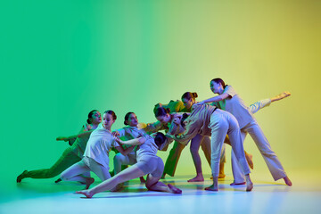 Group of beautiful school girls wearing white clothes dancing together on gradient background in neon light. Contemporary dance style