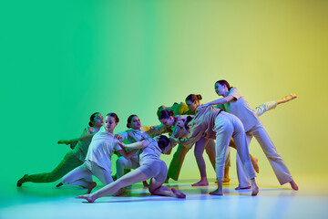 Group of beautiful school girls wearing white clothes dancing together on gradient background in...