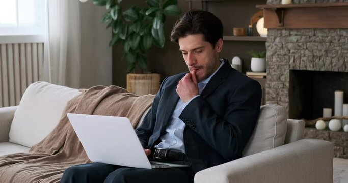 Thoughtful businessman coming up with a brilliant idea while sitting on sofa and working on laptop