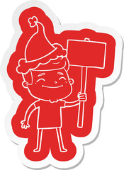 happy quirky cartoon  sticker of a man with placard wearing santa hat