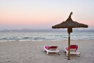 Sun loungers with umbrella on the sandy beach of Alcudia, Mallorca