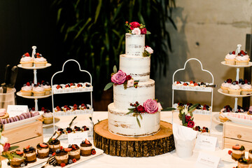 Weiße Hochzeitstorte und Dessertbuffet mit Cupcakes und Macarons