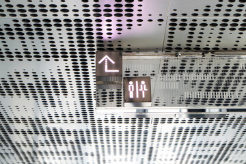 Signs depicting men and women or individuals to walk up to top. On public Steel or iron signboard. People walking and symbol hanging on ceiling is made of modern aluminum. Sunlight coming from behind.