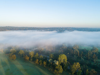 Waves of rolling mist at dawn over treetops and river in Singleton