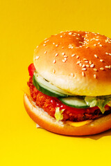 Delicious juicy burger with cutlet and vegetables on a yellow background, side view. Creative concept of fast food and burger macro
