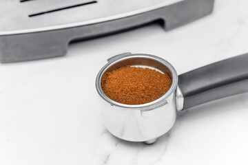 Coffee cone with ground coffee lie on marble table. Coffee machine at home