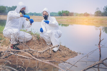 Scientists with protective suit holding a test tube with sample water in their hands. Water pollution examine concept