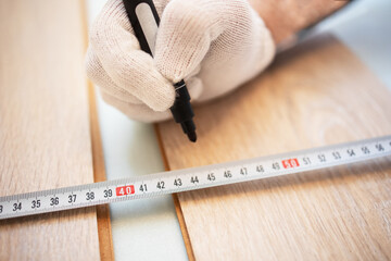 Close up of a mans hand in white gloves, an automatic measuring tape, a black felt-tip pen for...