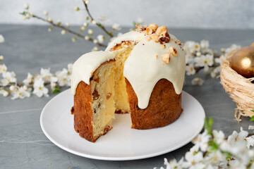 Piece of Easter cake on plate decorated with spring flower branches