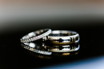 Nahaufnahme von silbernen Eheringen mit Diamanten und Spiegelung auf schwarz